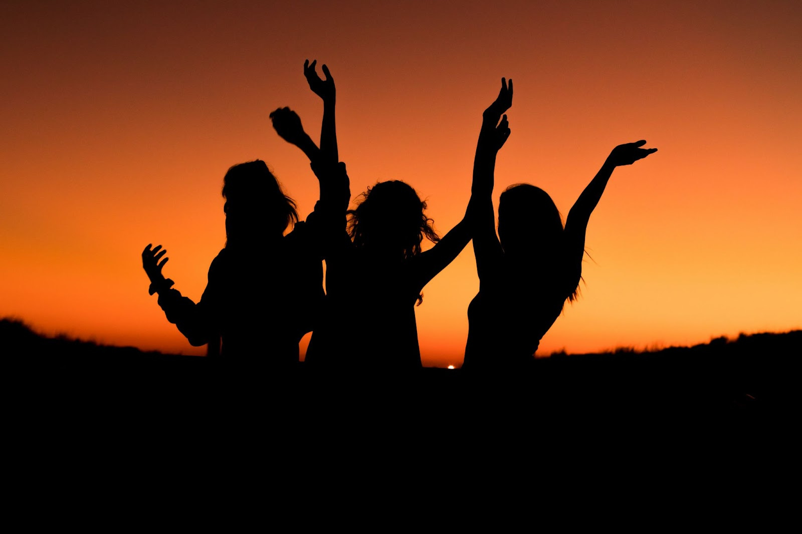 Silhouette of three women celebrating during sunset